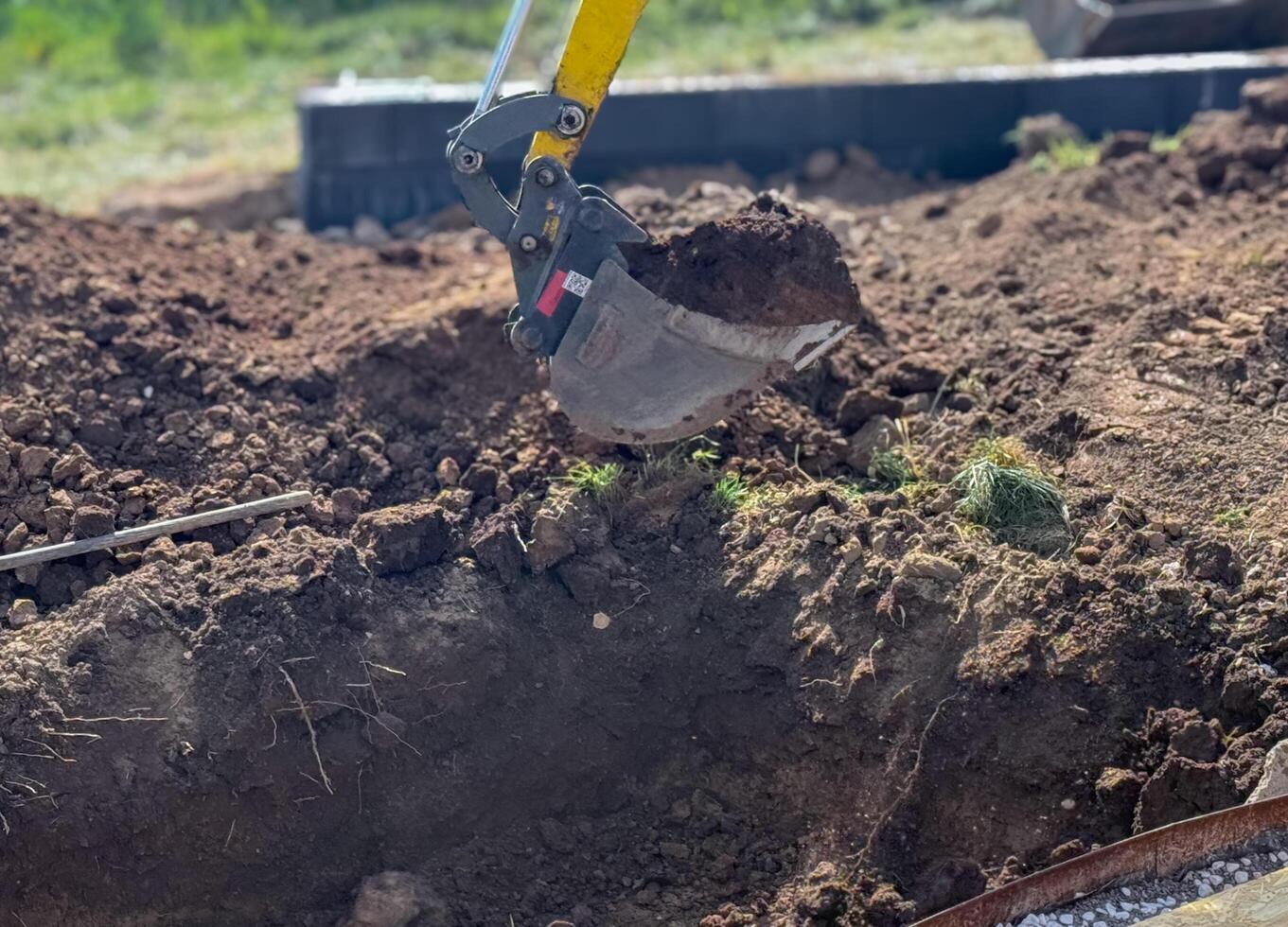 Close up view of excavator bucket digging ground . photo
