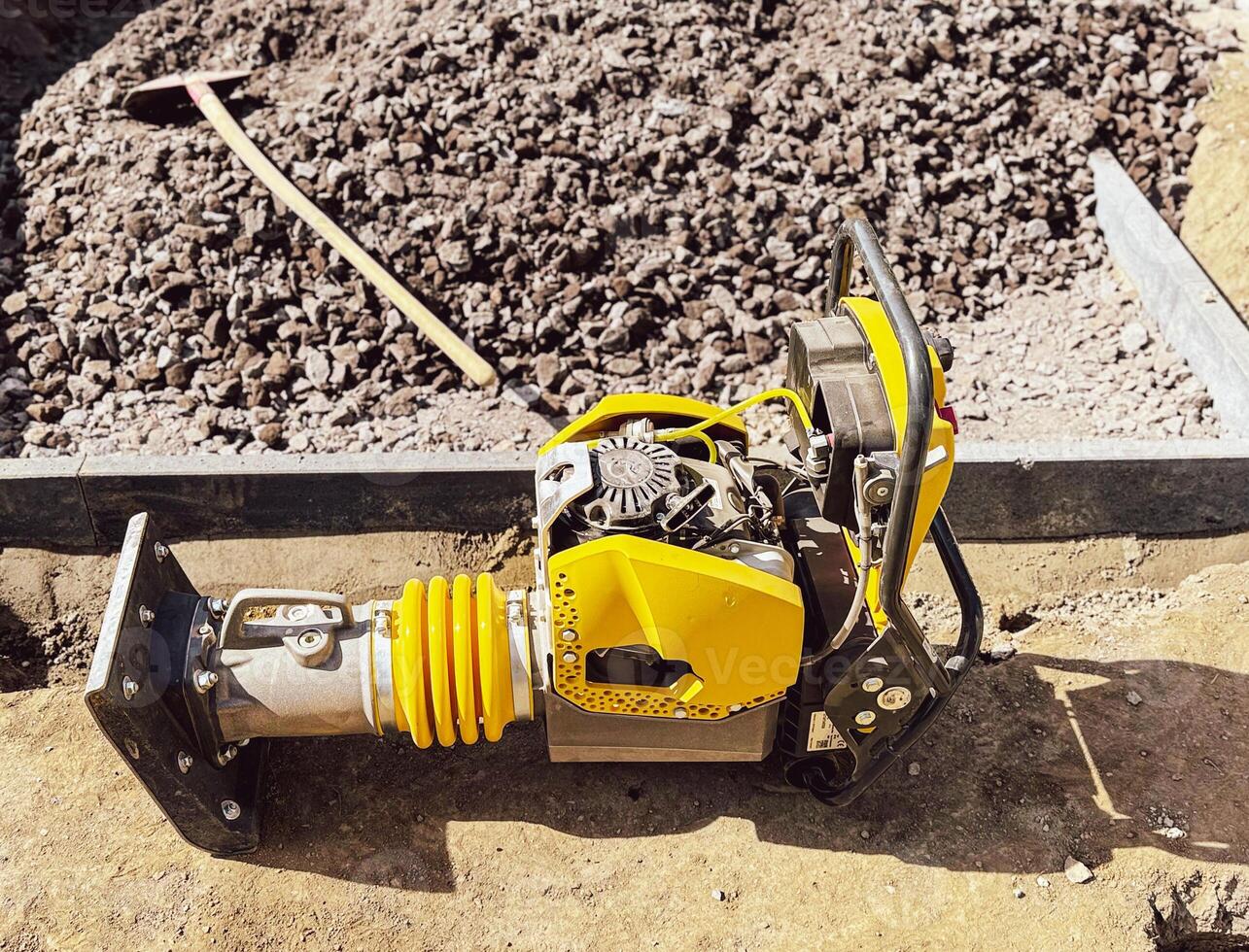 Small plate compactor, vibratory hammer, jumping jack machine, power tool at construction site photo