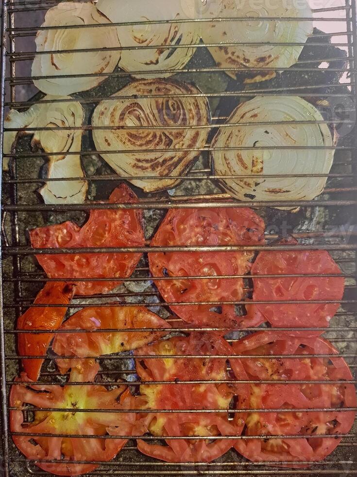 A close-up view of onions and tomatoes as they roast on the grill photo