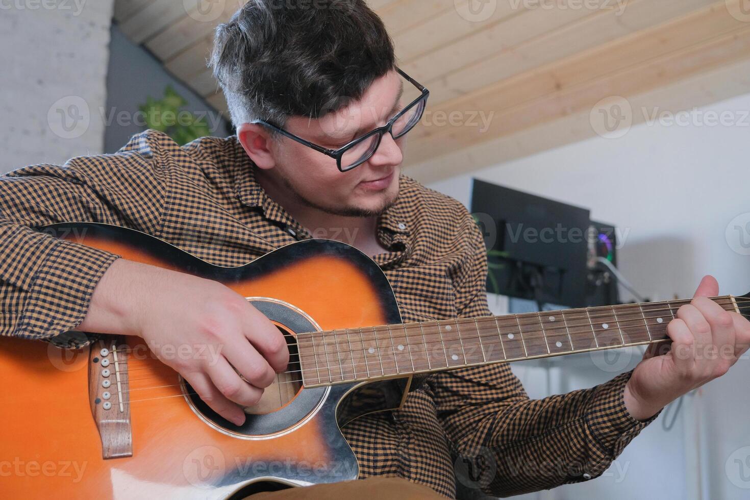 Young smiling man musician playing classical guitar at home photo