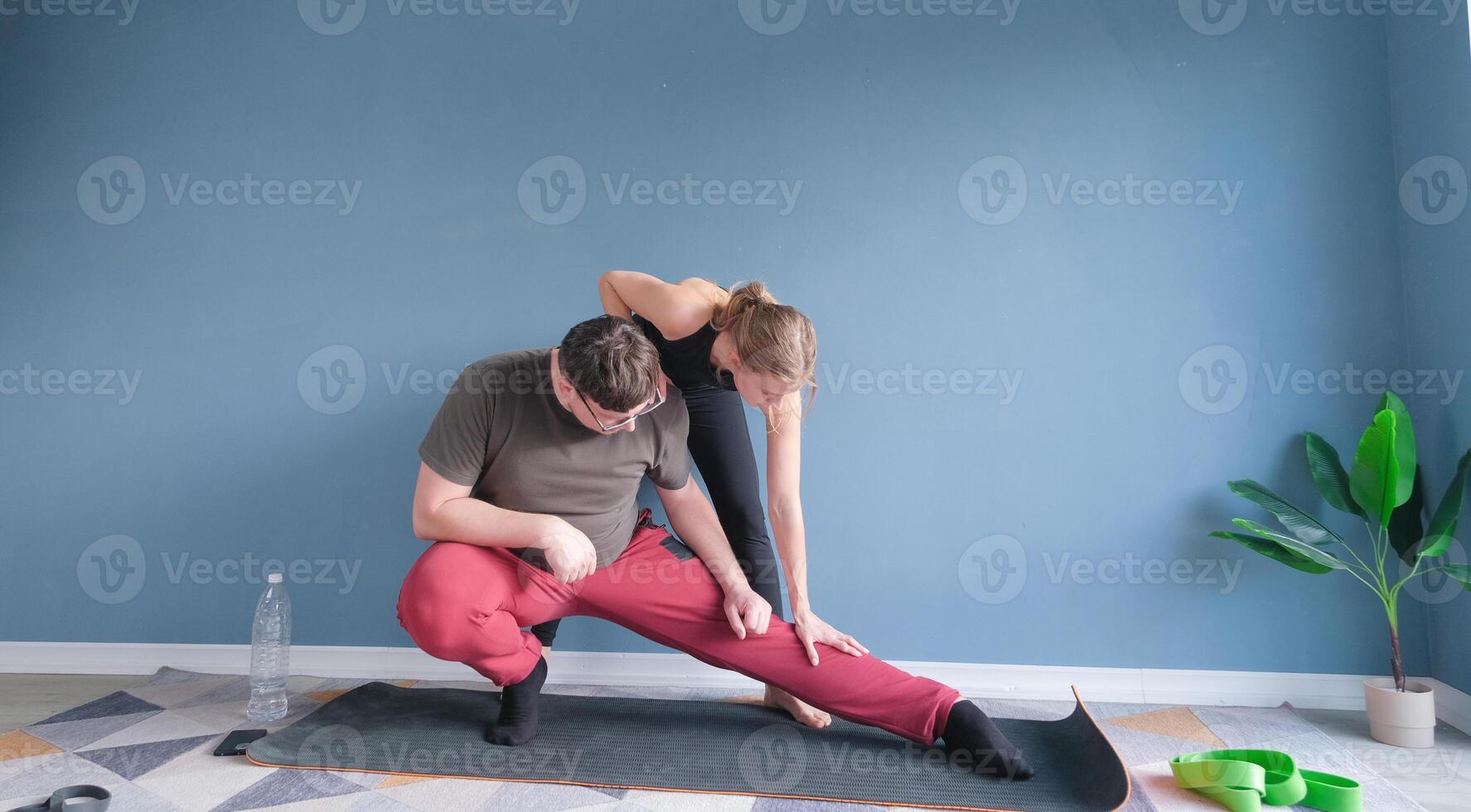 yoga teacher helping young man to stretch muscles photo