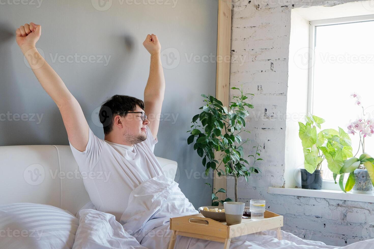 Young man waking up and having breakfast in bed photo