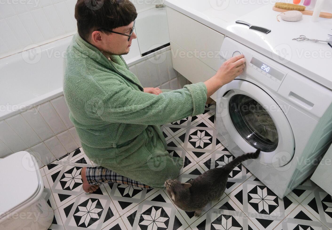 man doing laundry in the bathroom loading washer photo