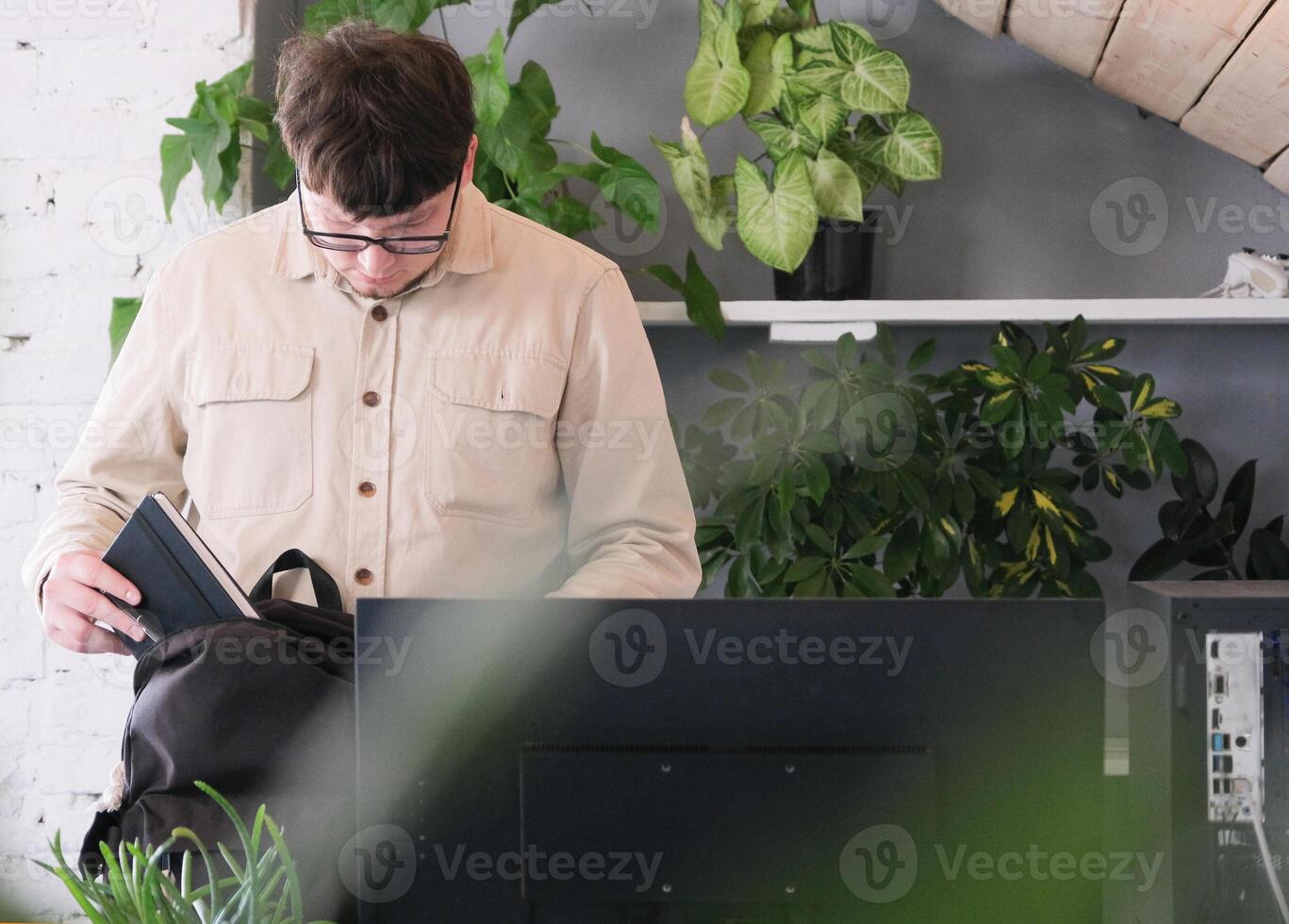 millennial man in casual clothes using smartphone and computer while spending time at home photo