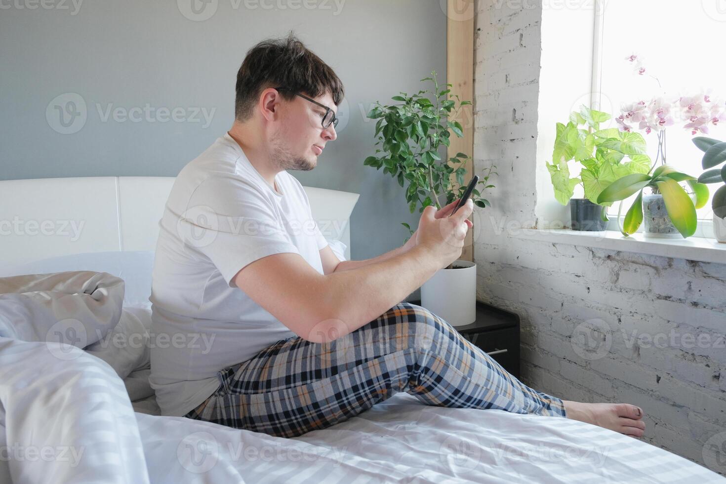 man waking up and having breakfast in bed and using smartphone photo