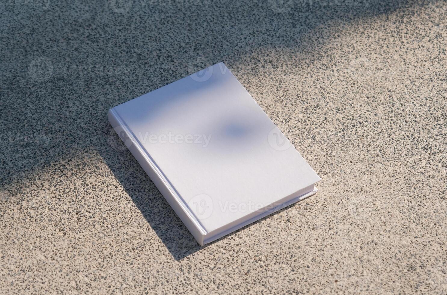 empty book mockup on stone floor or pavement outdoors, shadow overlay photo