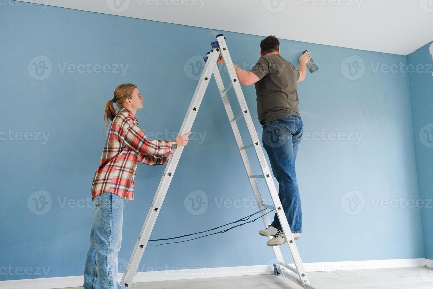 couple renovating house apartment painting wall together. Family man woman repair flat themselves. photo