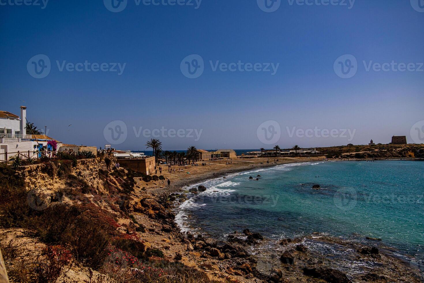 A coastal landscape reveals a serene beach with turquoise waters gently meeting the rocky shoreline photo