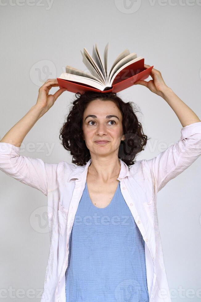 A beautiful woman or girl with a red book. Emotions, smiling. Copy space. photo