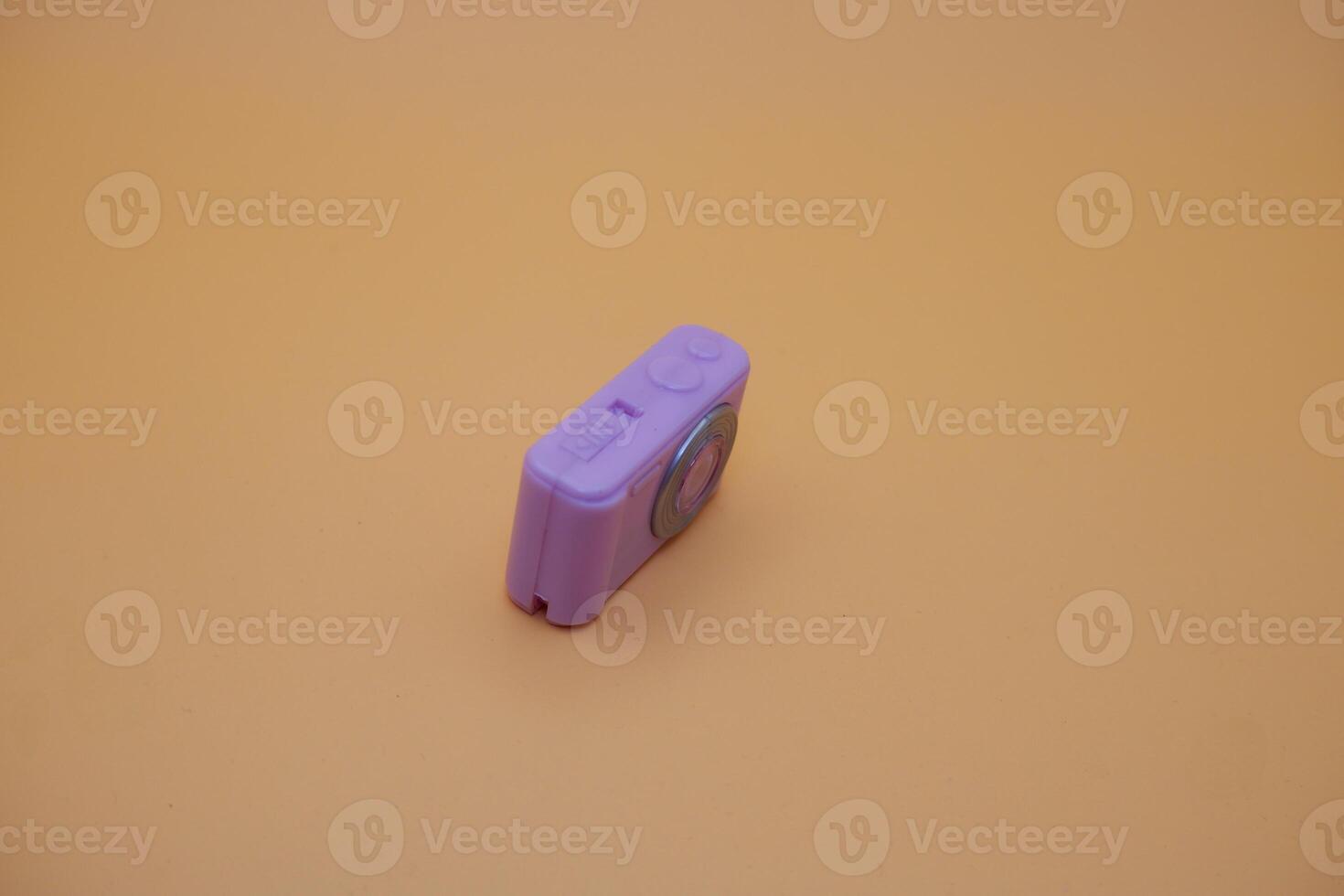 Small Purple Camera Toy on Beige Surface with Soft Shadows photo