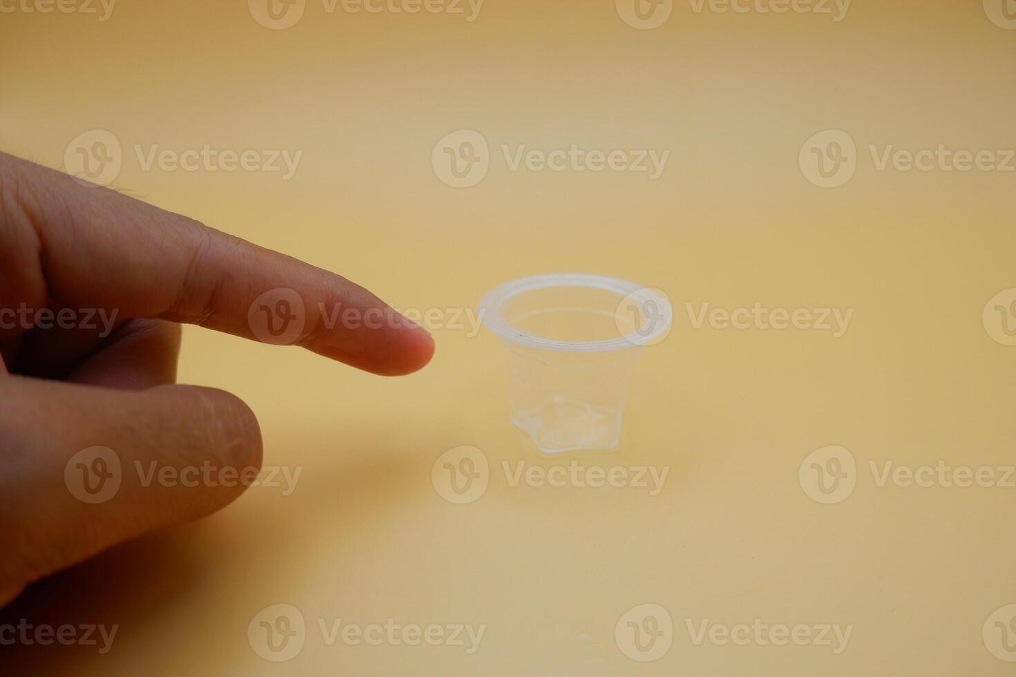 Finger Pointing at a Small Jelly Snack Cup on Neutral Background photo
