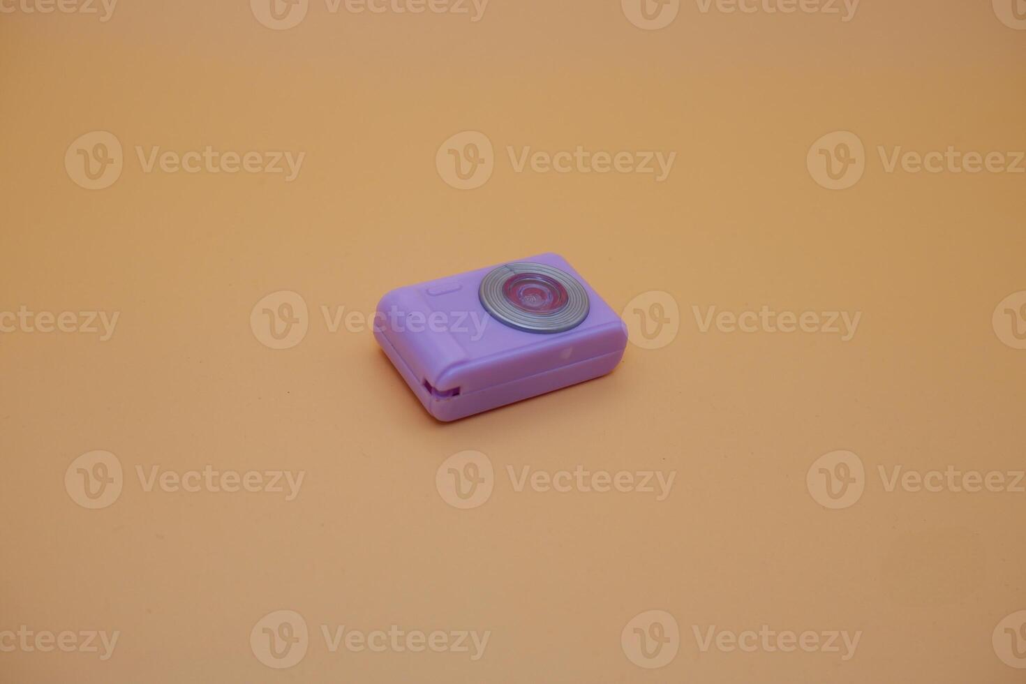 Mini Purple Toy Camera Lying on Orange Background photo