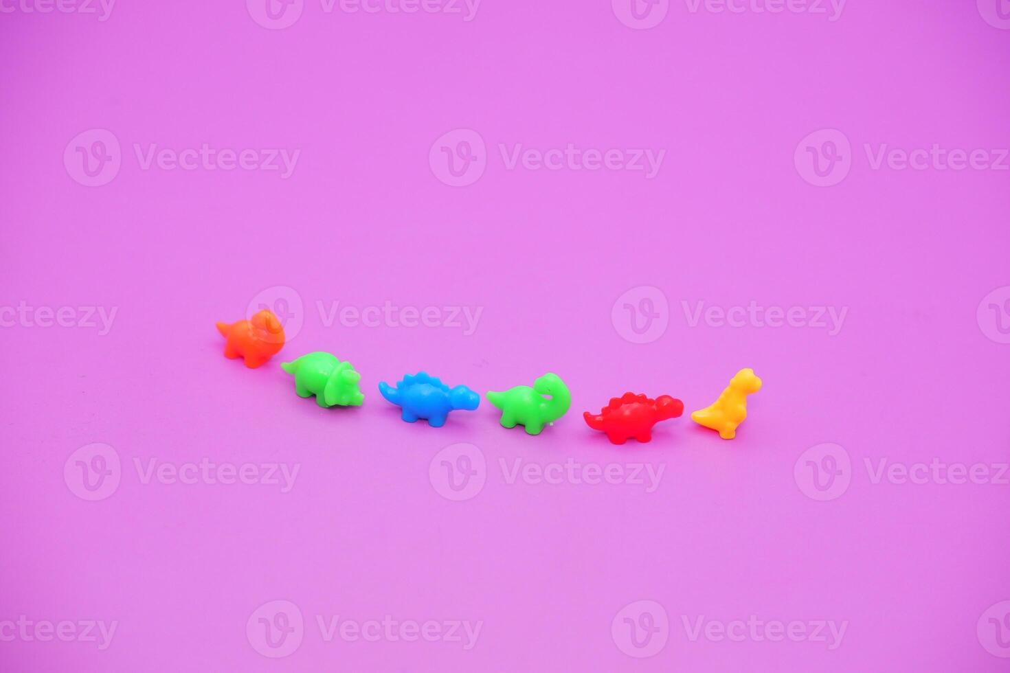 Bright Plastic Dinosaur Figurines Arranged on Violet Surface photo