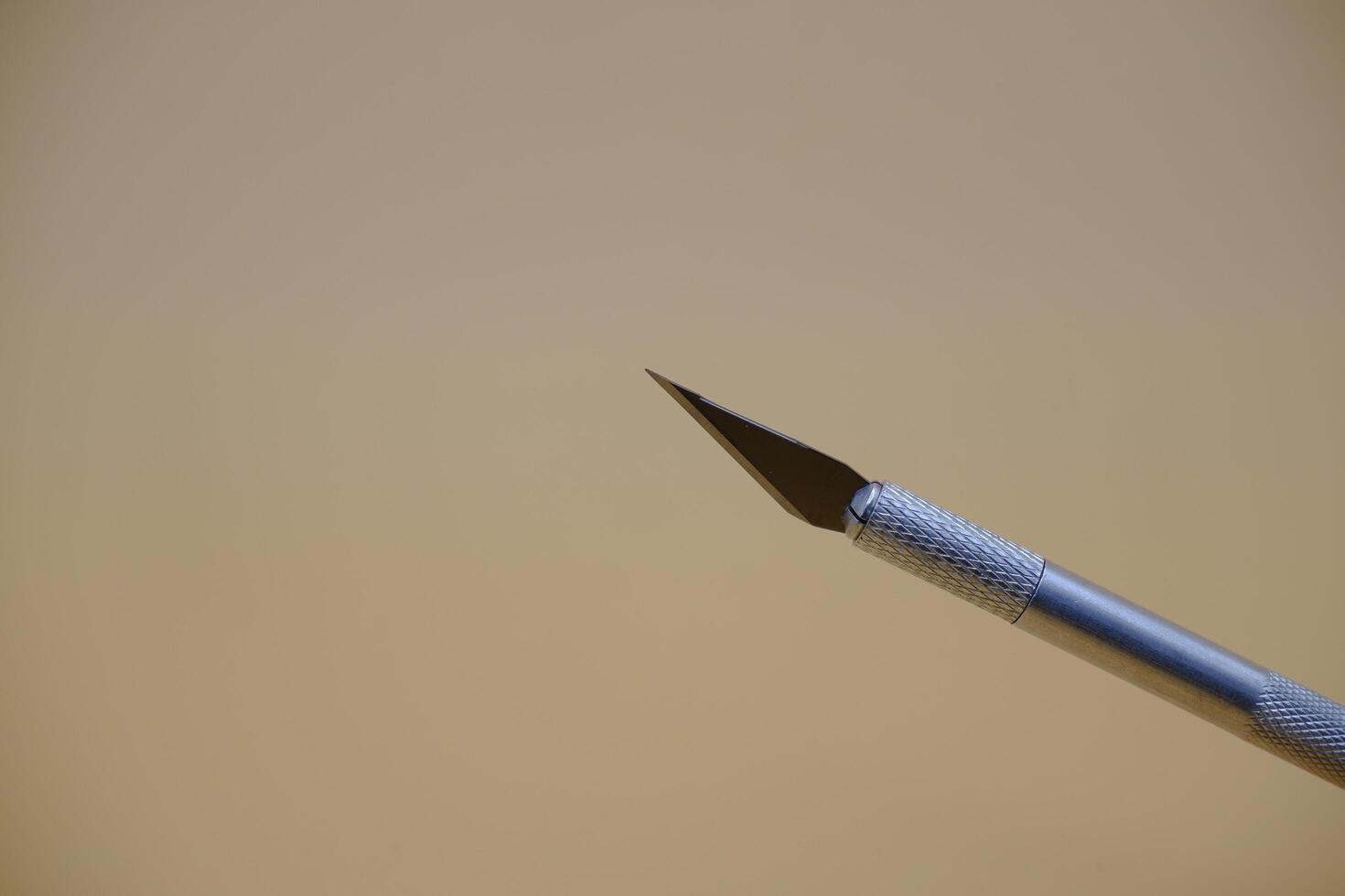 Pen Cutter Tool Isolated on Beige Surface photo