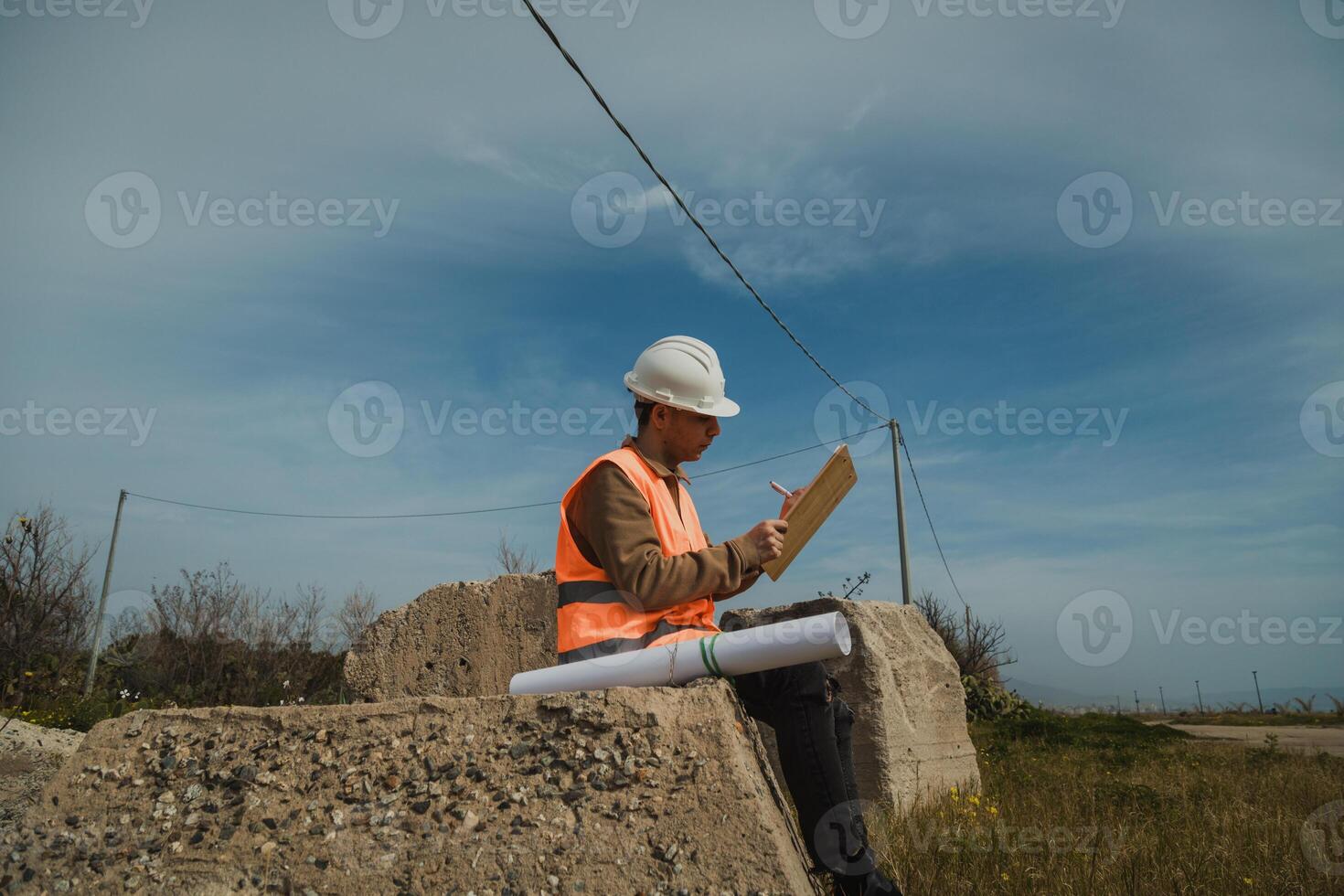 Engineer Outdoor Sitting On A Rock And Taking Notes photo
