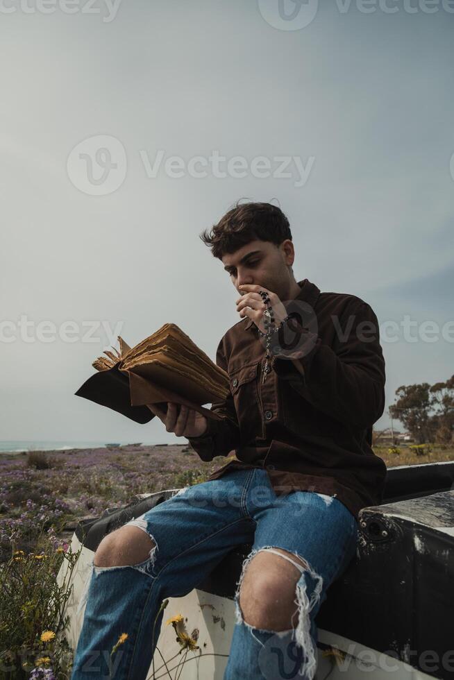 Christian Man Reading A Prayer On The Bible Book While On The Beach During Summer photo