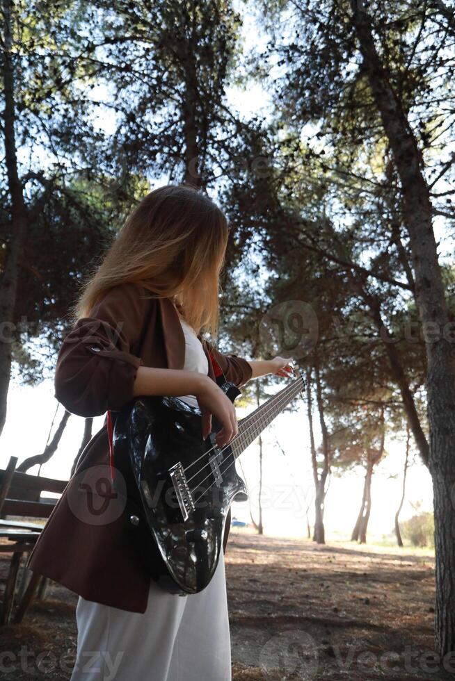 Girl Adjust Handles To Tune Bass Musical Instrument In Park photo