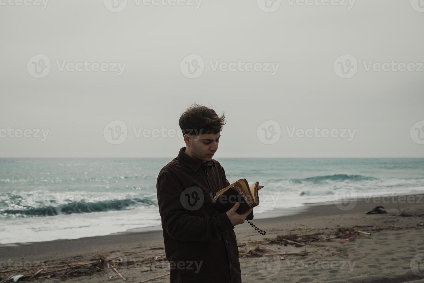Man Flipping The Pages Of The Bible Book While Praying Near The Ocean Stormy photo