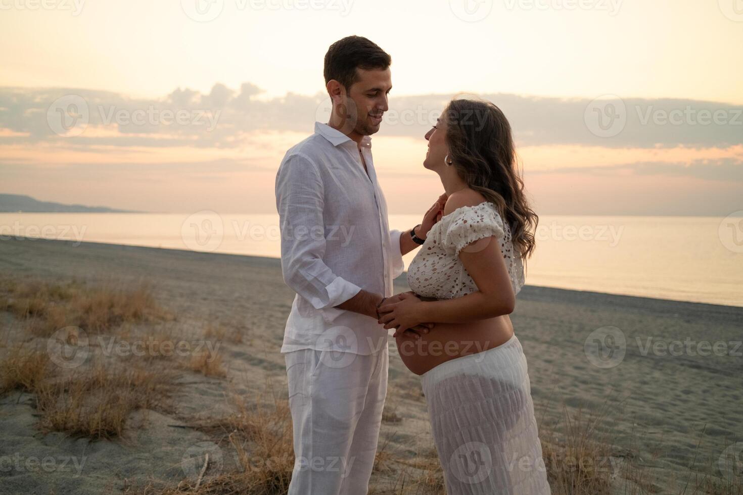 Pregnant Couple Sharing Special Moments at Sunset Beach photo