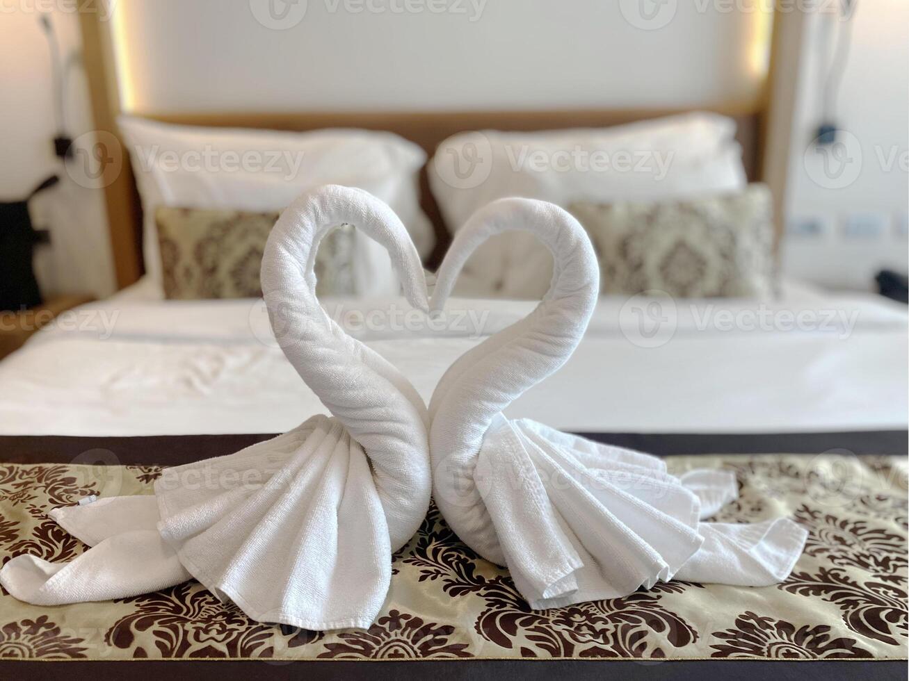Romantic swan towel art arranged in a heart shape on a bed in a luxury hotel room, symbolizing love and hospitality blurred background. photo