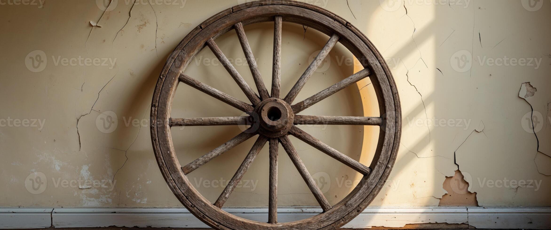 An old wooden wheel is leaning against a wall photo