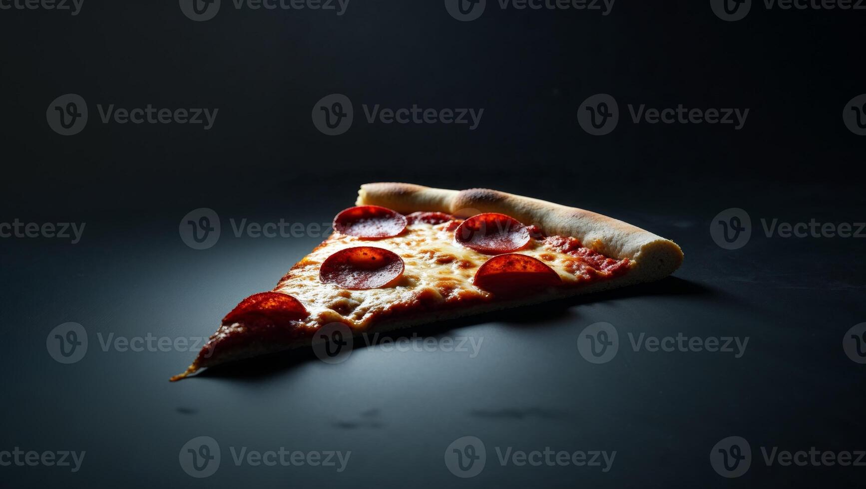 A slice of pepperoni pizza on a black surface photo