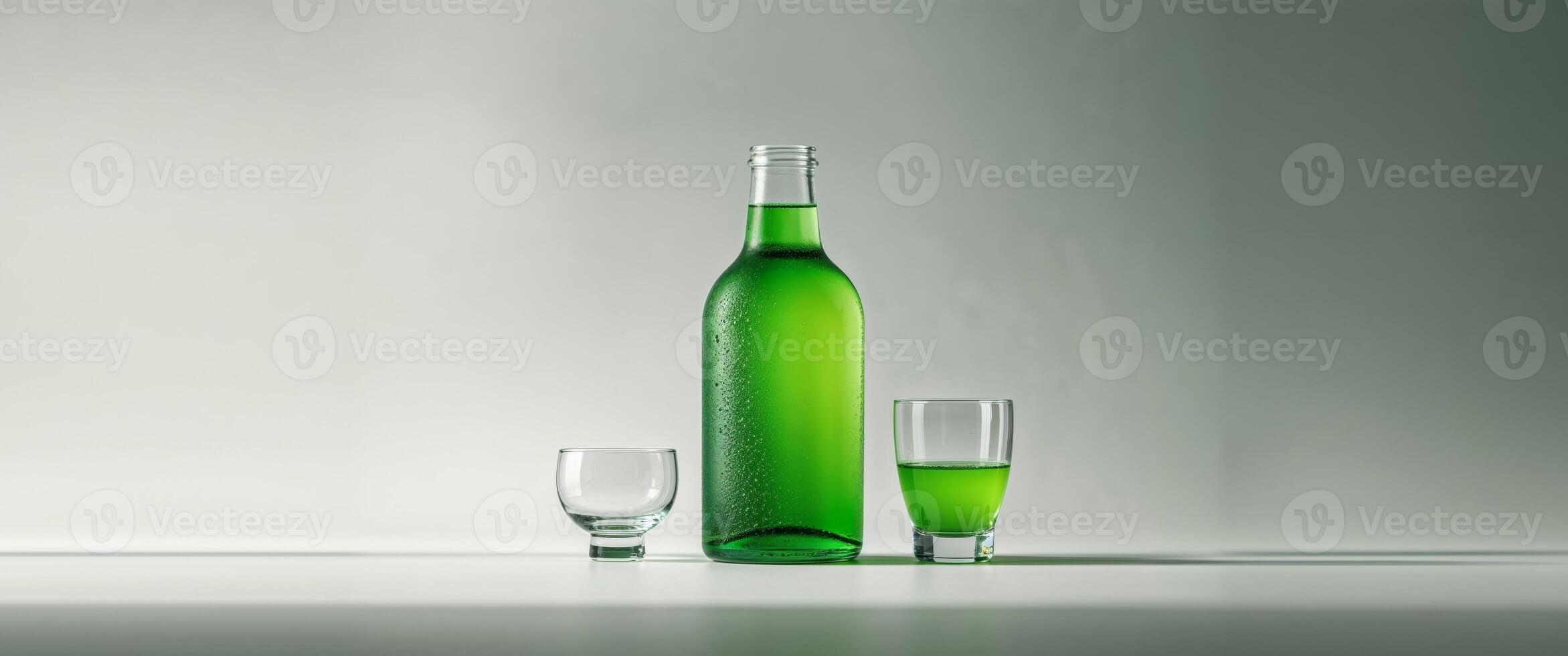 A bottle of green liquid and two glasses photo