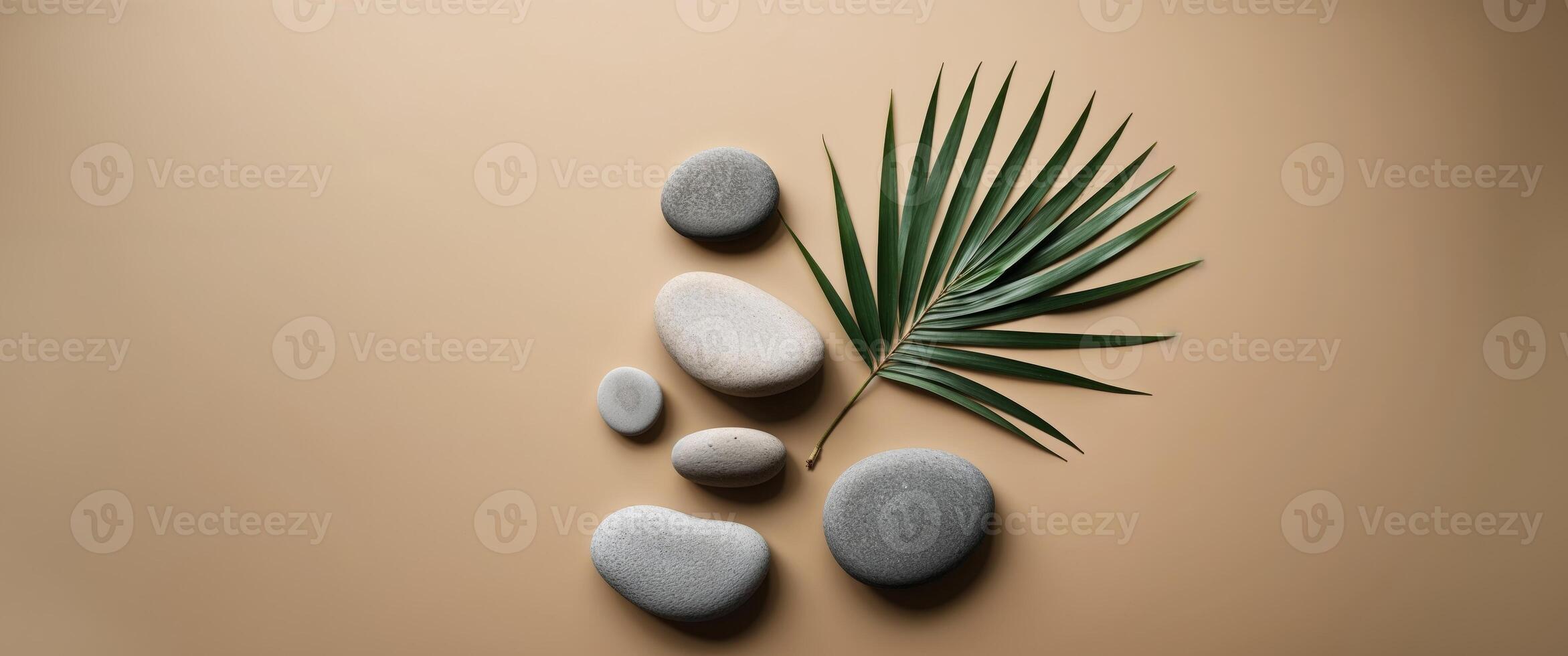 Smooth stones and palm leaf on a beige background. photo