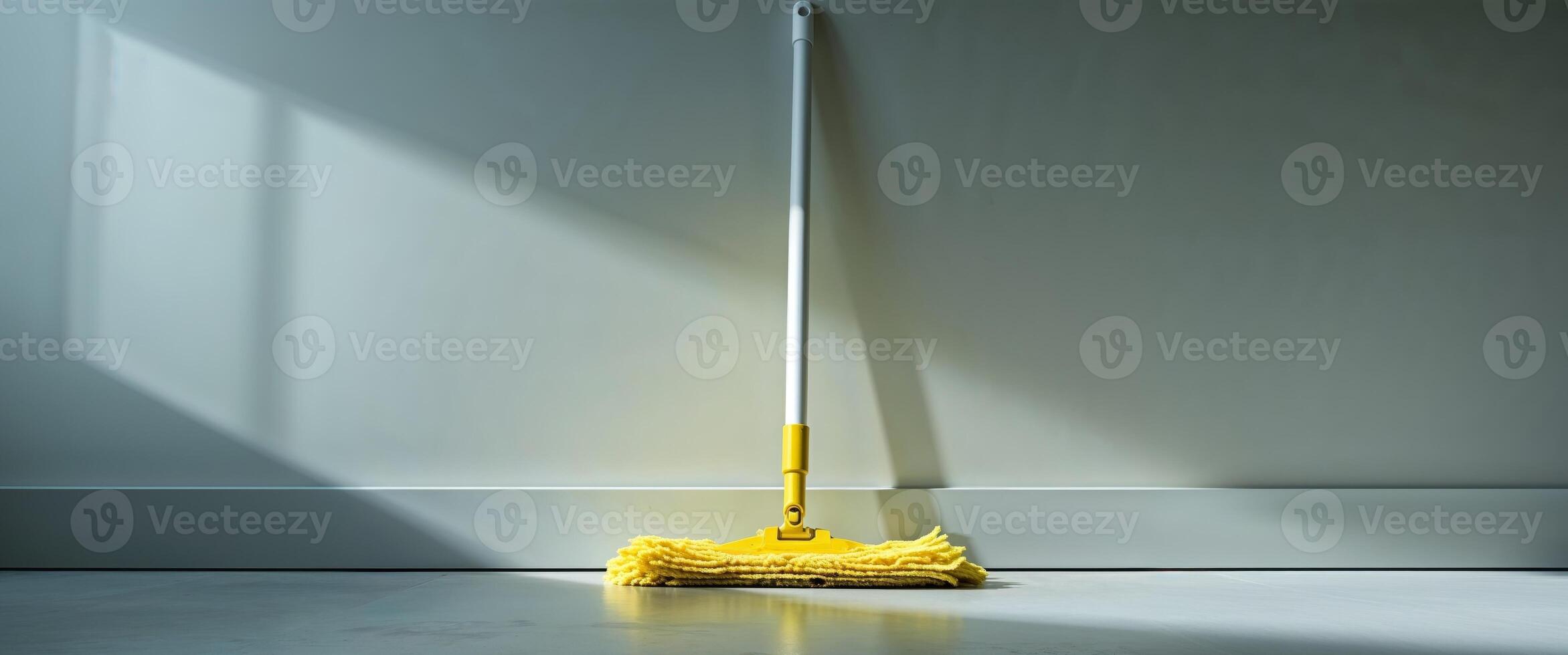 Yellow mop with a white handle is leaning on the floor photo