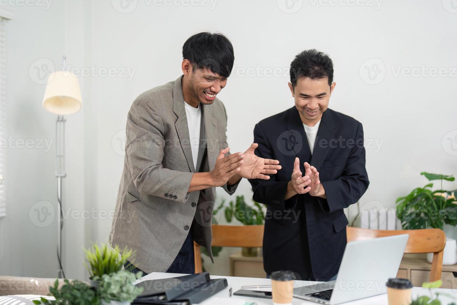 Business Celebration and Achievement. Two professionals clapping and celebrating a successful project completion in an office. photo