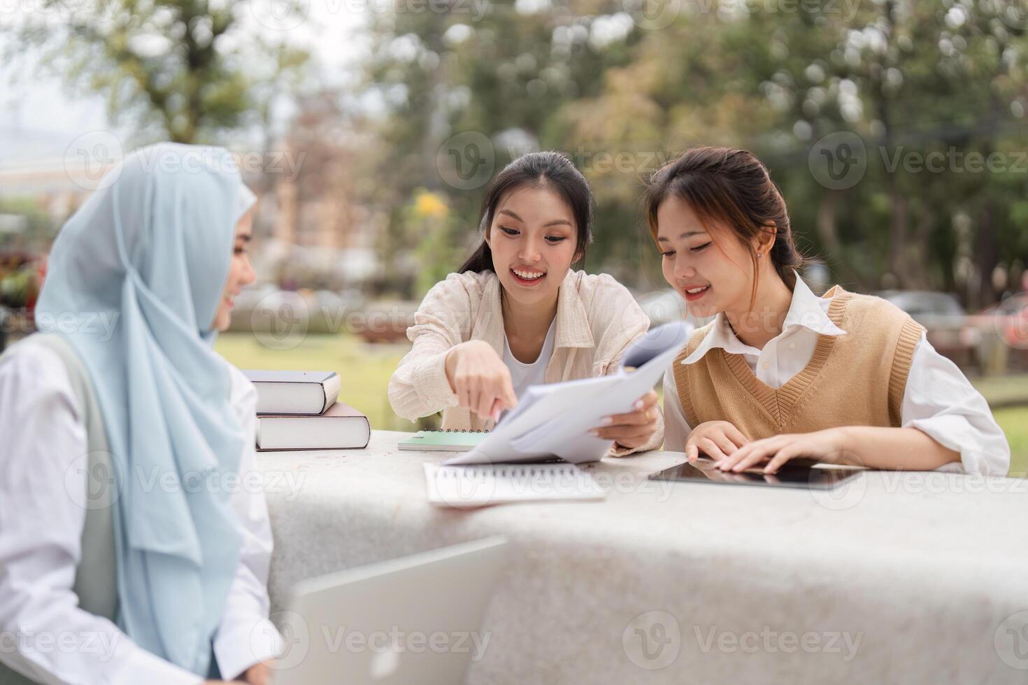 Diverse university students collaborating on academic materials outdoors in study session. photo
