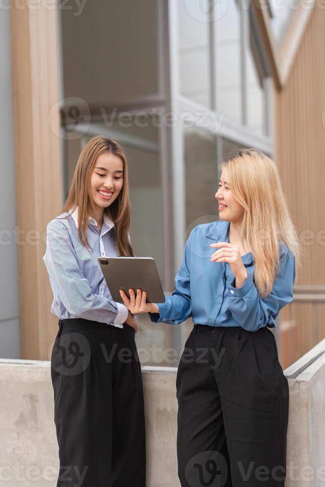 Diverse women sharing information on a tablet, showcasing teamwork and collaboration. photo