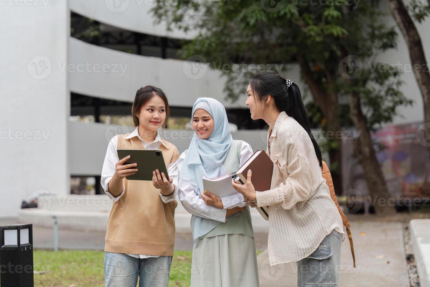 Diverse university students using a tablet, collaborating on academic projects outdoors. photo