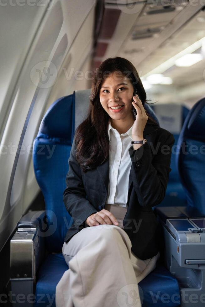 Business travel with a young woman smiling while on a call inside an airplane photo