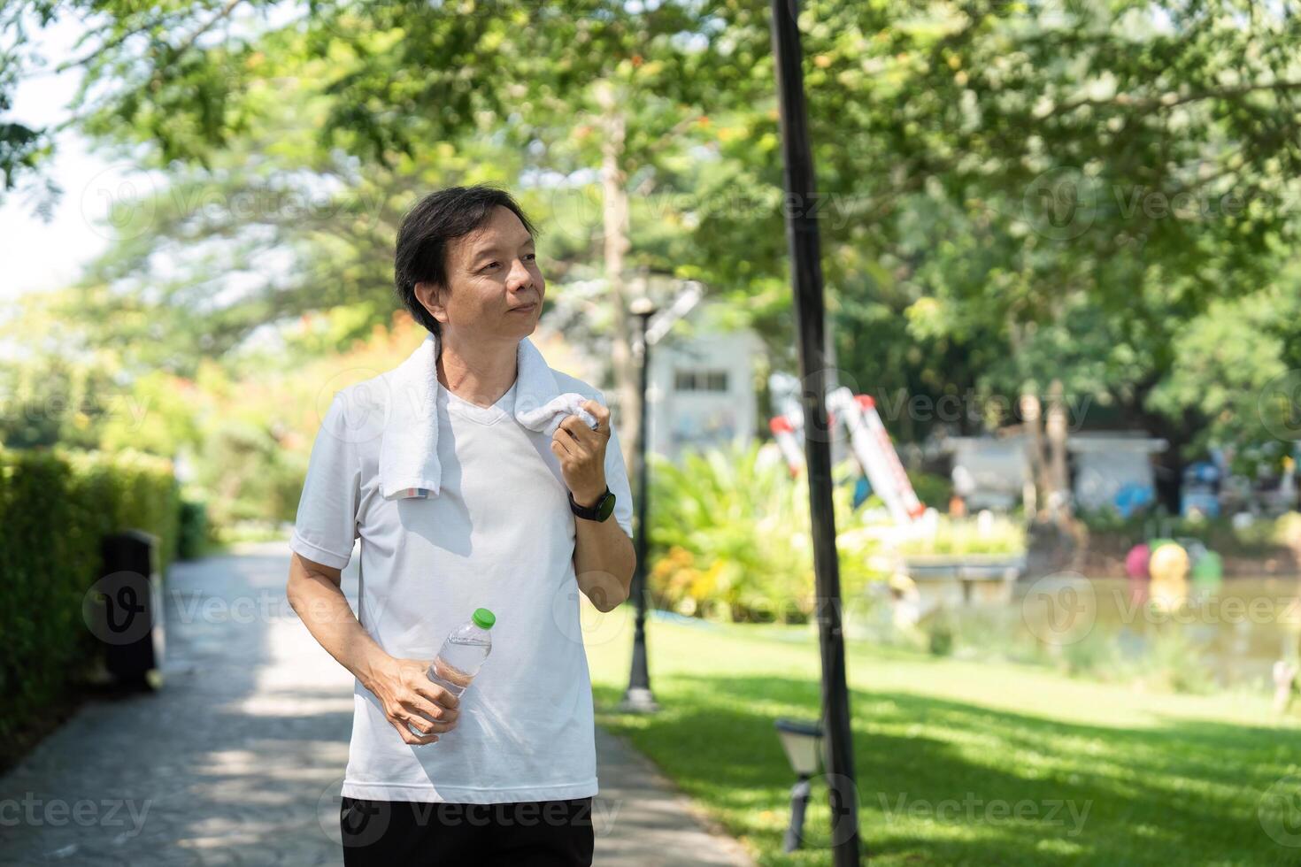 Wellness and Hydration. Man enjoying a refreshing drink of water during a morning walk in the park. photo