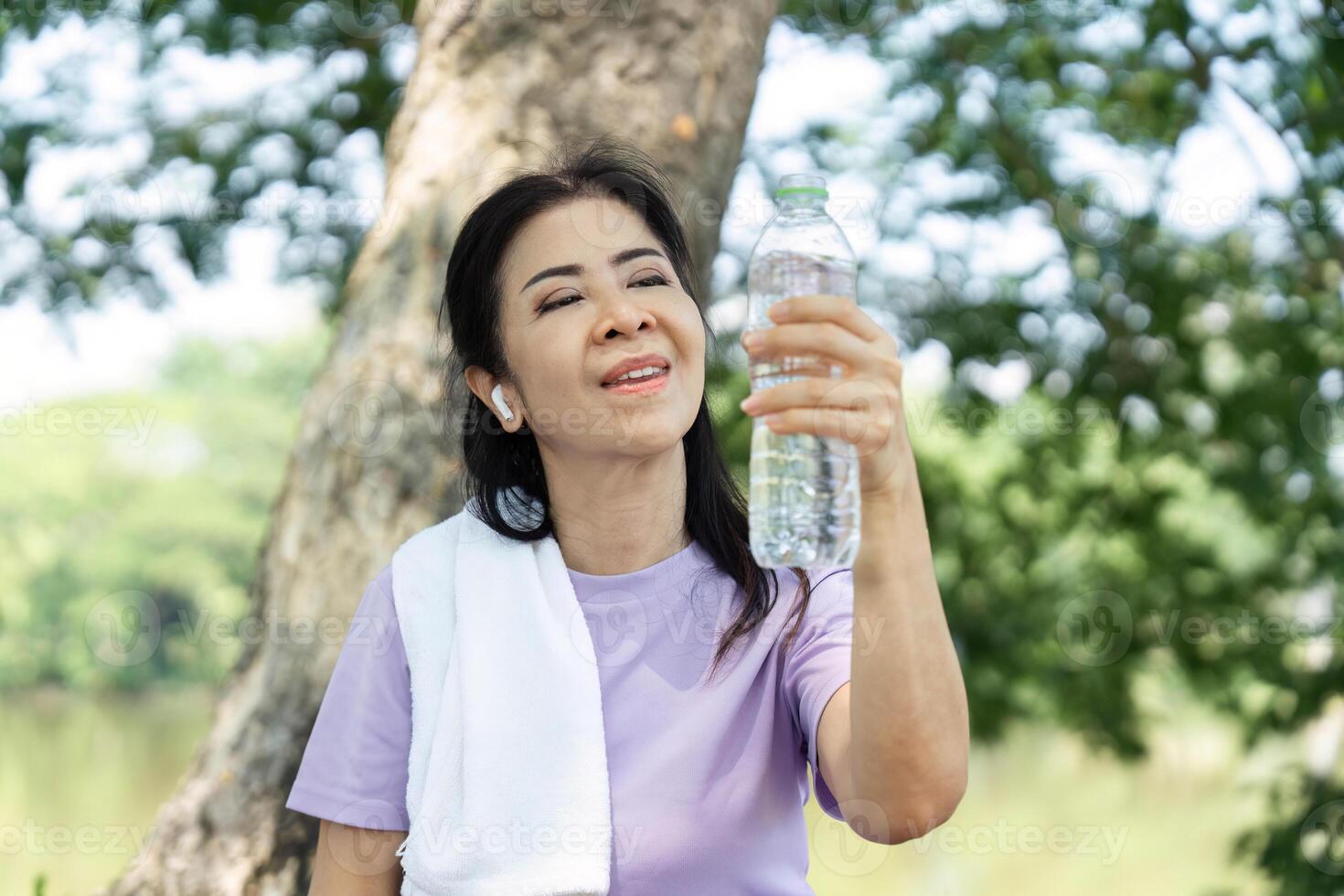 Wellness and Refreshment. Woman celebrating hydration with a water bottle after exercising outdoors. photo