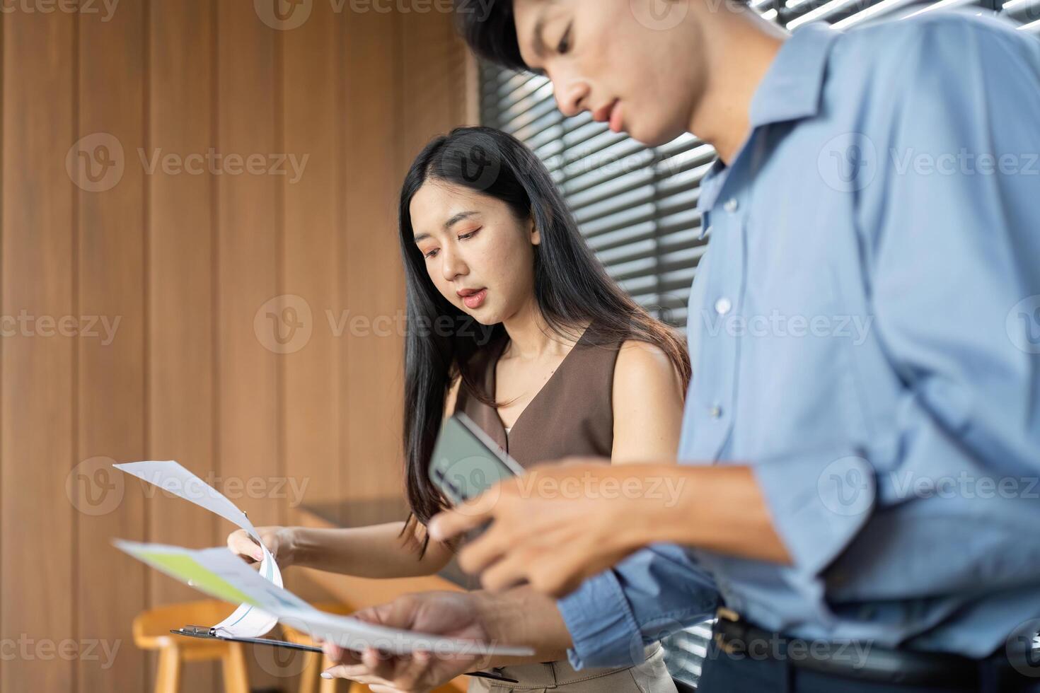 Business Interaction and Document Review. Professionals discussing project details in a stylish office setting. photo