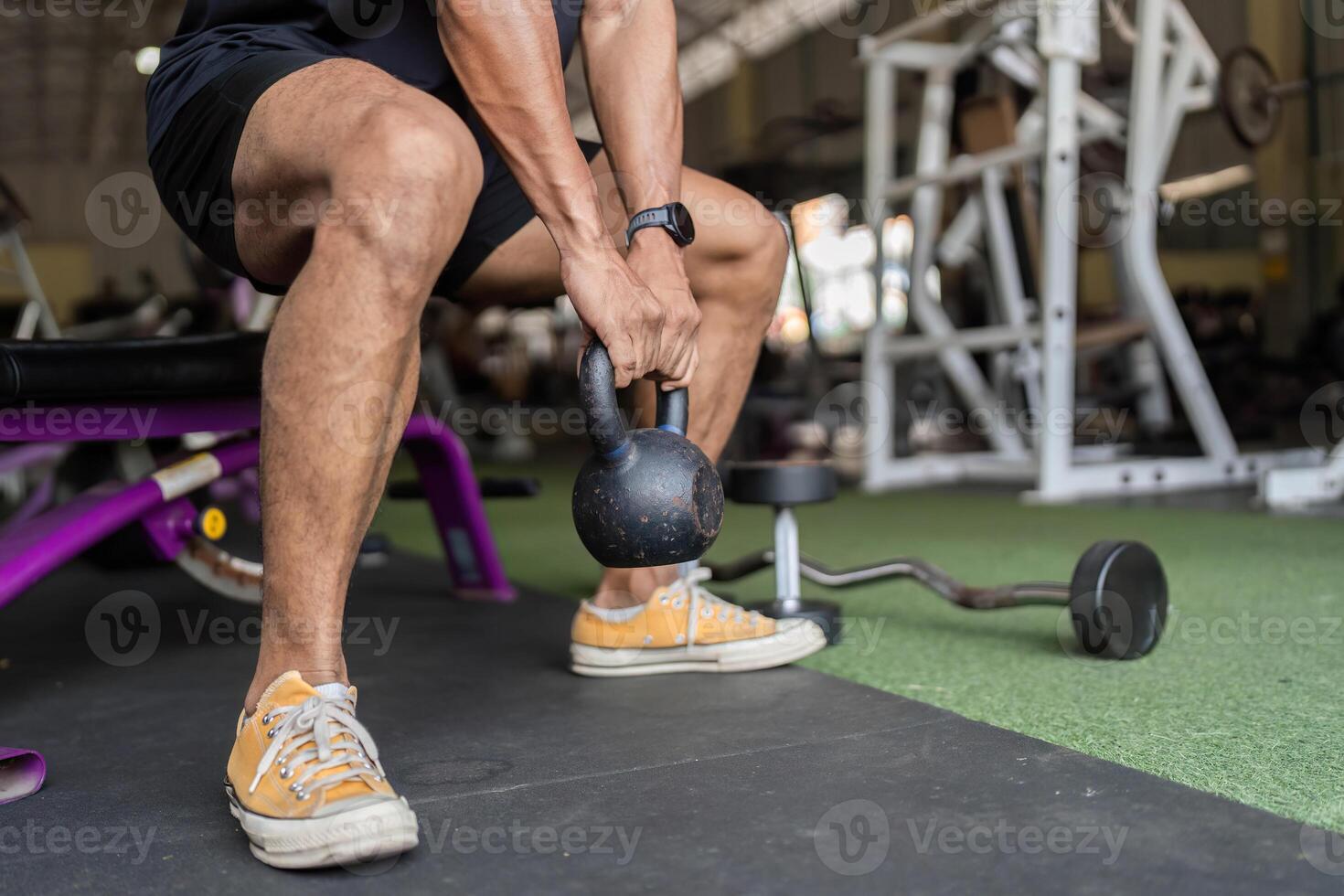 Fitness Routine. Close-up of young man lifting kettlebell in gym. photo