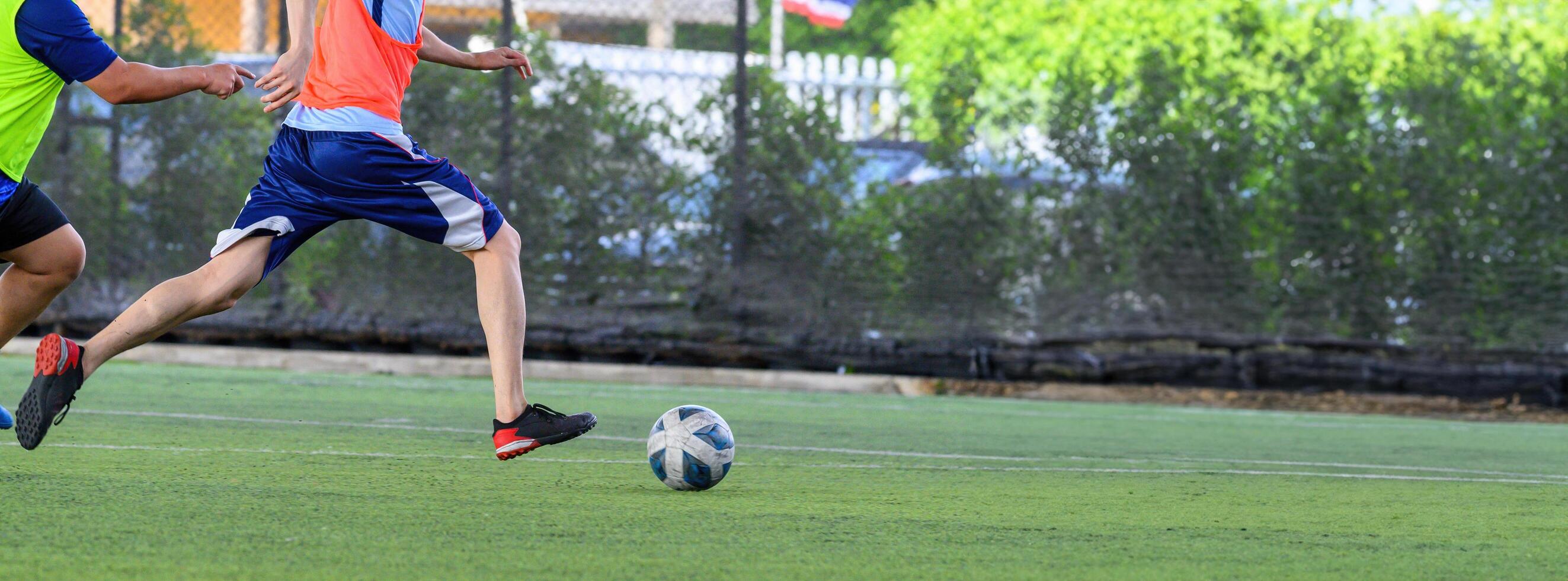 Soccer players in action during game on grass field focusing on their legs and ball, showing dynamic movement and competitive spirit in bright outdoor light photo