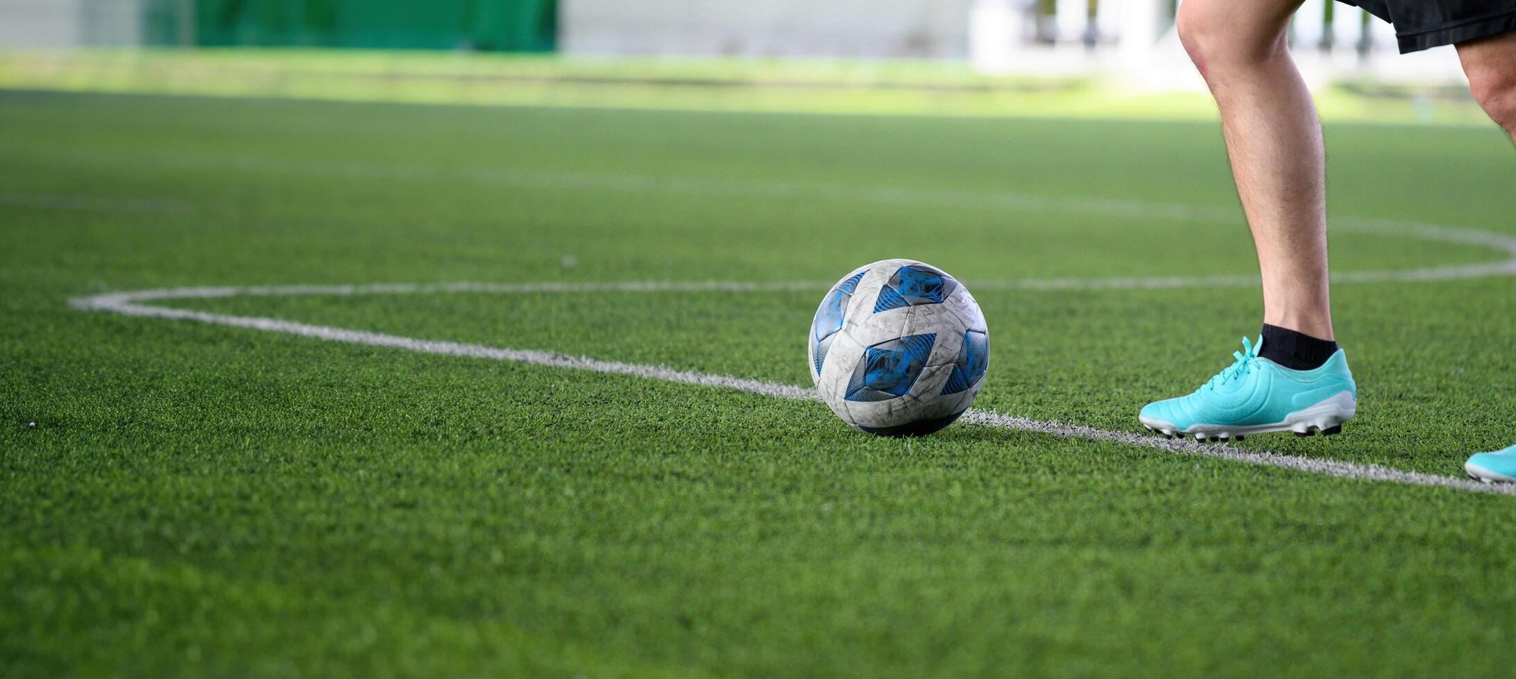Soccer ball on green grass field with player wearing blue cleats preparing to kick during game, focusing on legs and ball in action on sports field photo