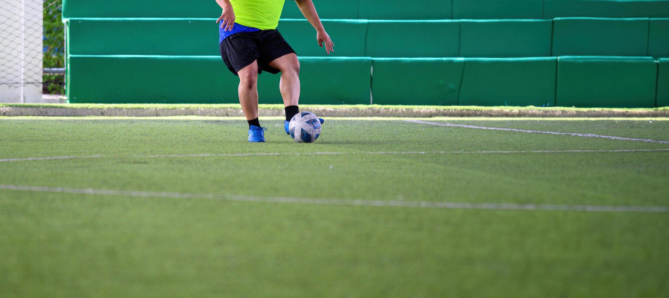 Soccer player controlling ball on green grass field during game, wearing bright yellow shirt and black shorts, focused on action with blue cleats photo