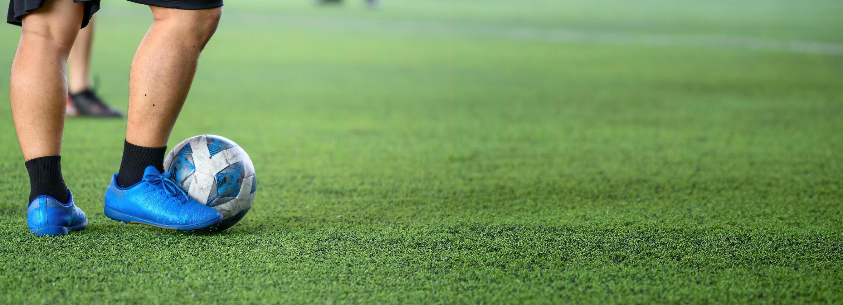 Soccer player wearing blue cleats controlling ball on green grass field during game, focusing on legs and ball action in outdoor sports environment photo
