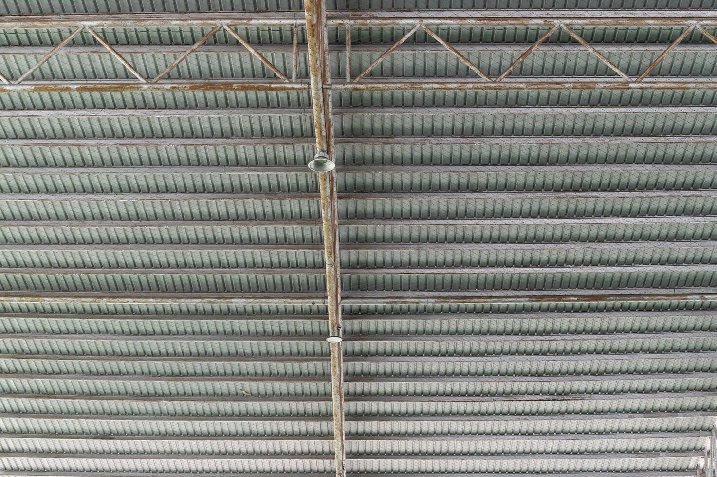 Industrial ceiling with exposed beams and structural elements in modern building, showing metal framework and lighting fixtures in organized pattern photo