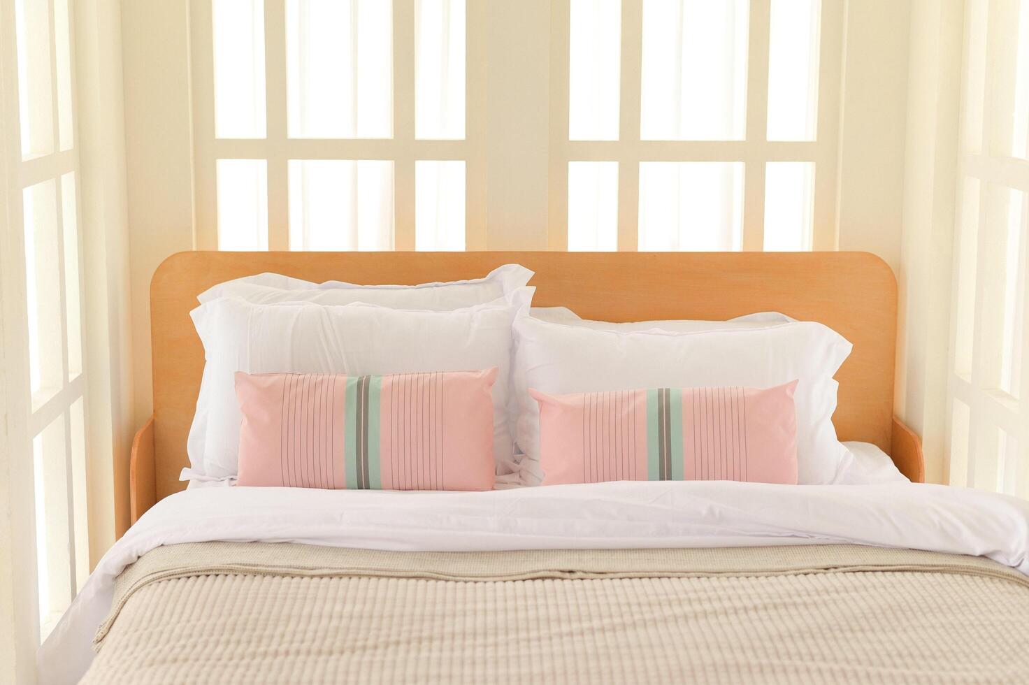 Cozy interior bedroom with wooden bed frame, white bedding, and soft pink pillows creating calm and inviting atmosphere photo