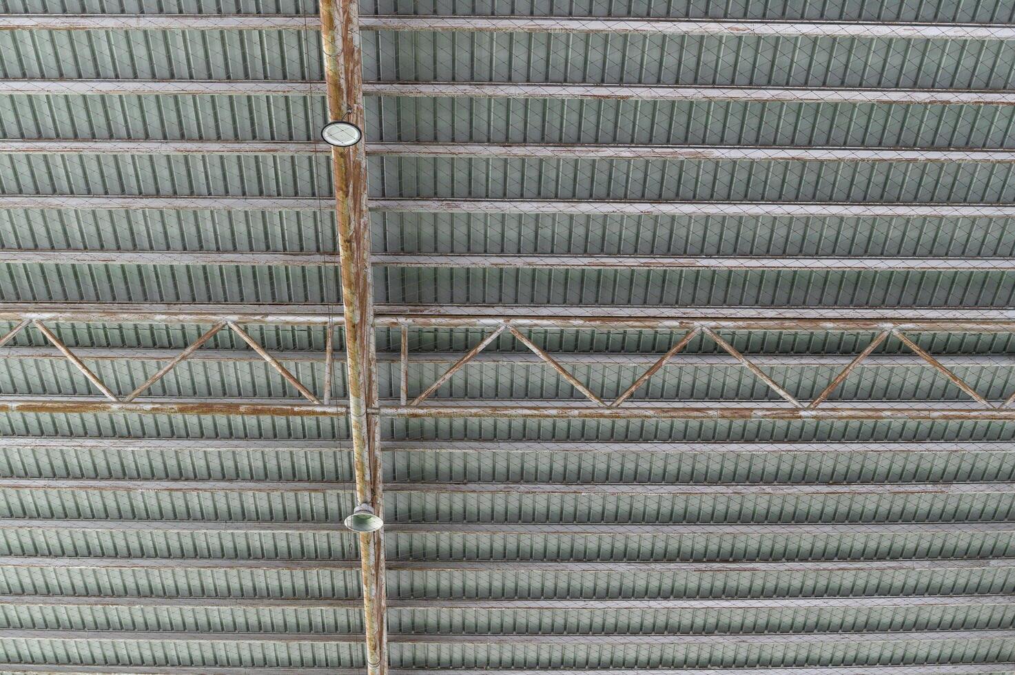 Industrial ceiling with exposed beams and structural elements in modern building, showing metal trusses and lighting fixtures in spacious interior photo
