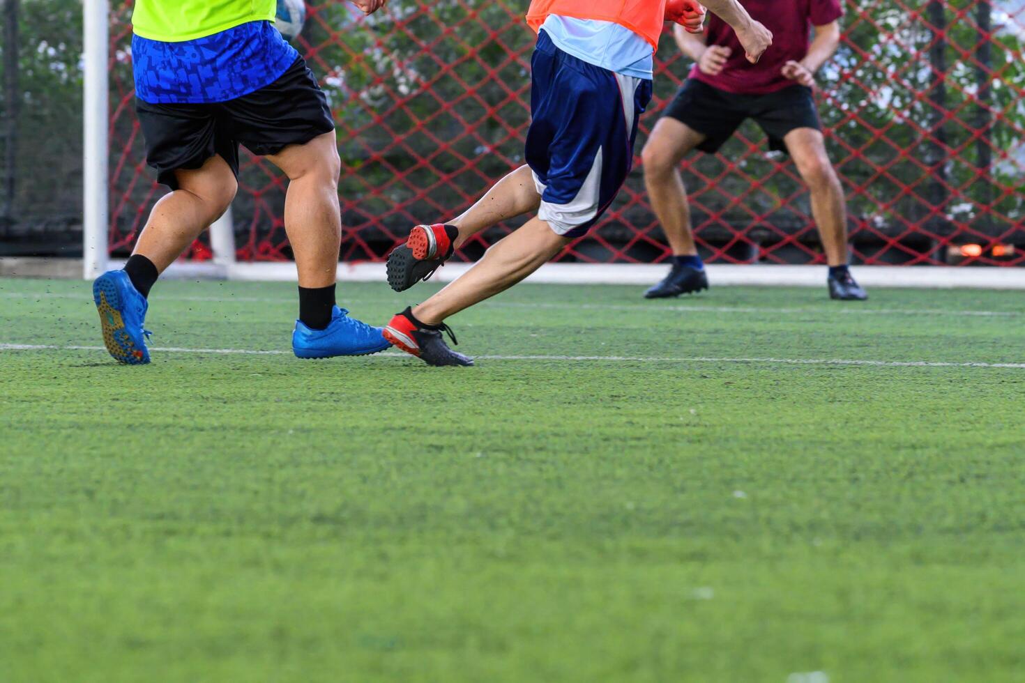Soccer players in action on green grass field focusing on their legs and ball near goal net during intense game photo