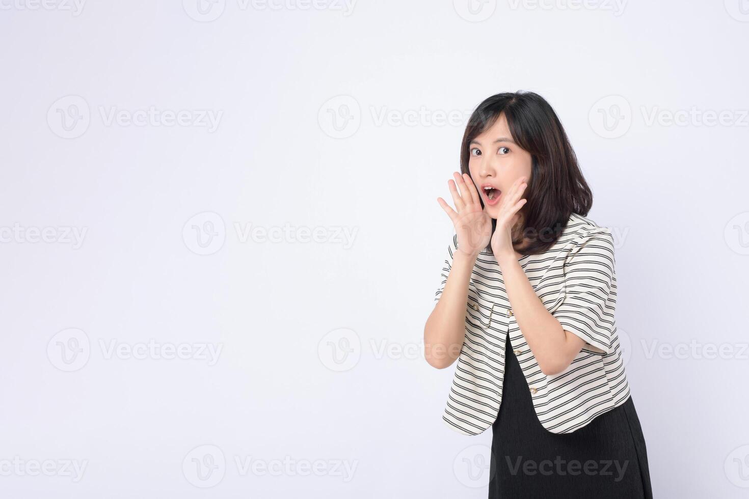 Southeast asian woman expressing surprise and excitement in advertising with striped jacket and black dress on white background photo