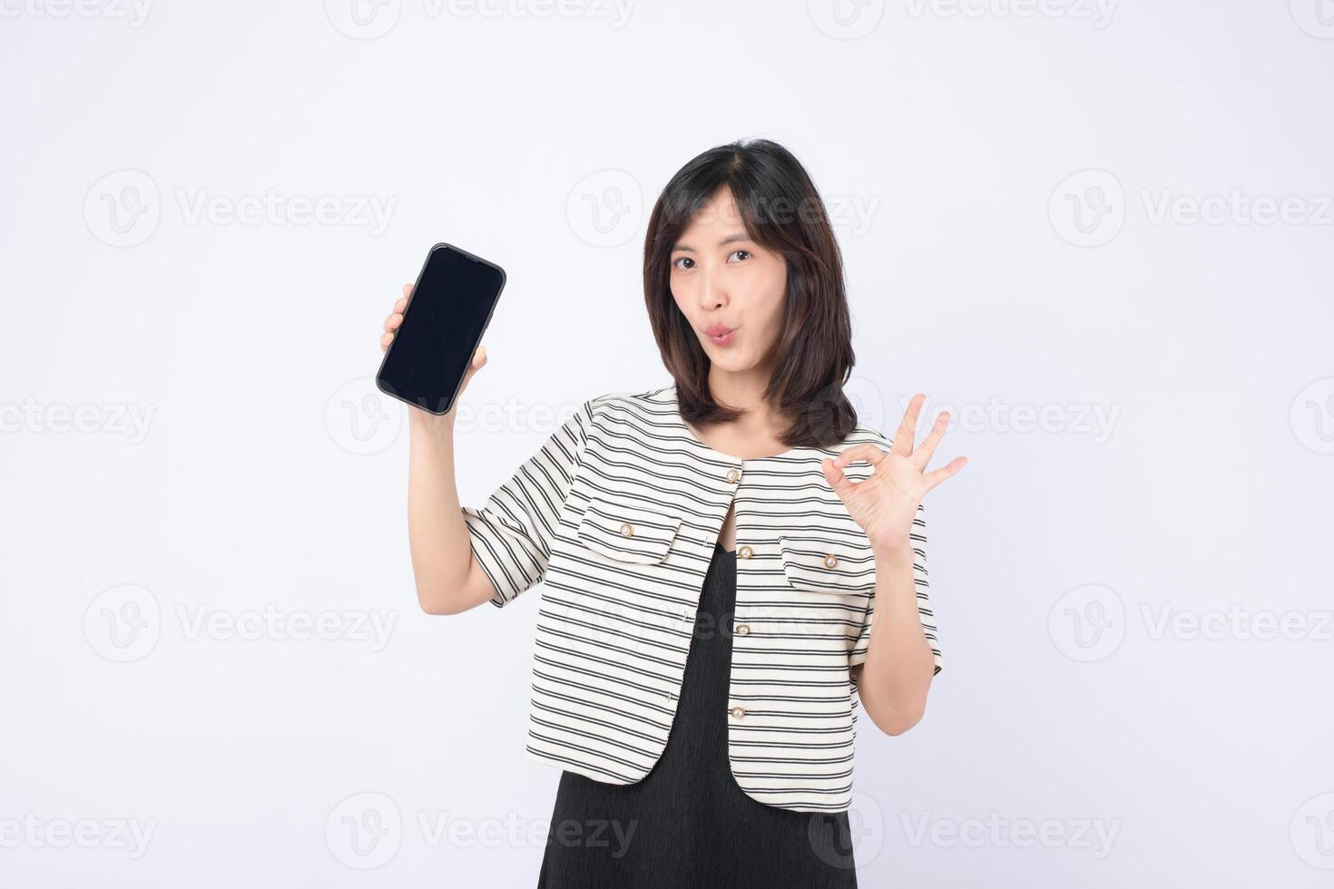 Southeast asian woman happily shows mobile phone with internet application while making okay gesture expressing satisfaction and confidence in technology photo