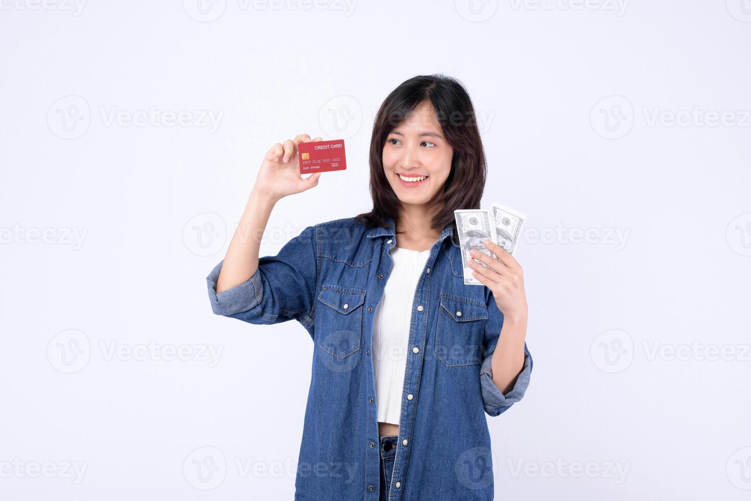 Southeast asian woman smiles happily holding credit card and cash money showing internet mobile application payment options for convenient financial transactions and shopping photo