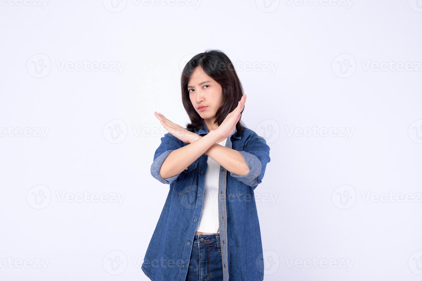 Southeast asian woman wearing denim makes advertising gesture with crossed arms showing refusal or stop in confident pose photo